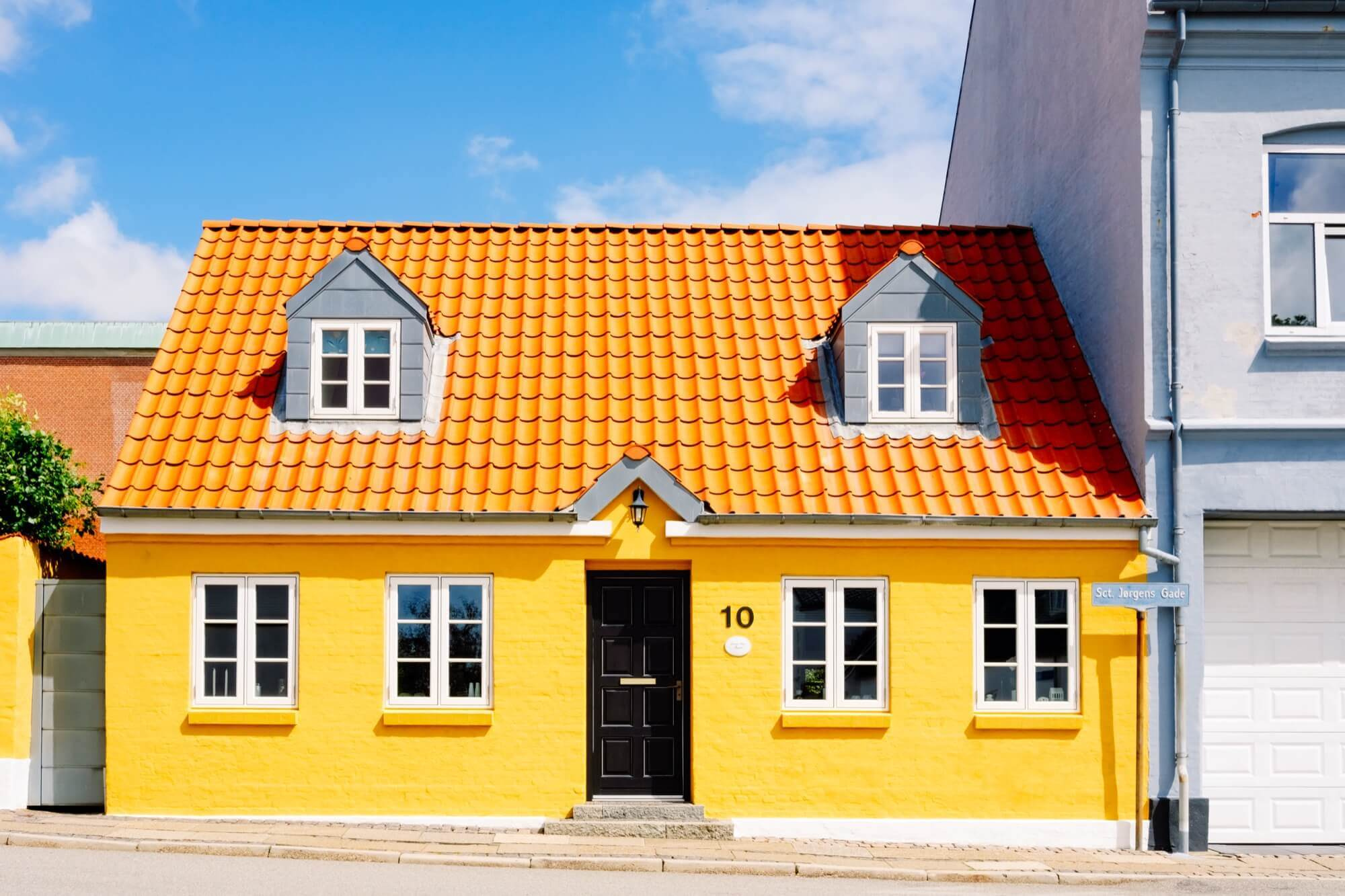 Plastered villa with orange tile roof and dormers, stylish facade painting that lifts the facade.